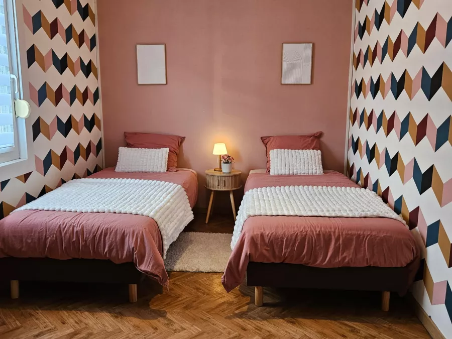 Chambre avec deux lits simples et papier peint graphique