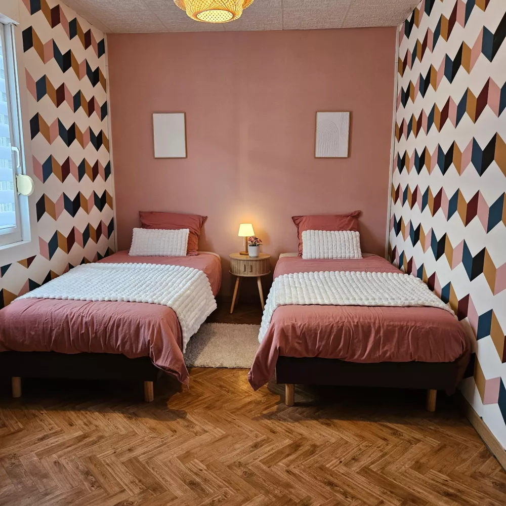 Chambre avec deux lits simples et papier peint graphique